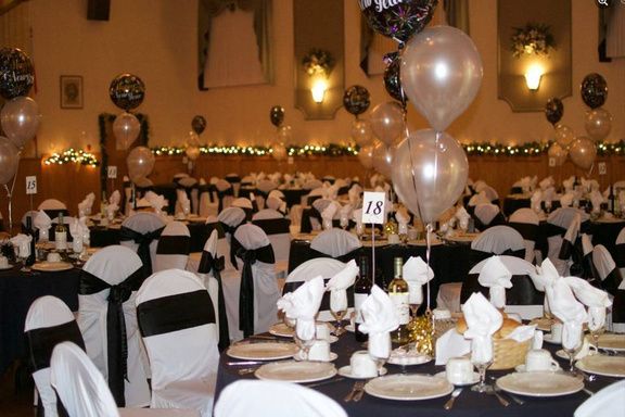 Eine private Feier im Saal mit Ballonen und festlich gedeckten Tischen