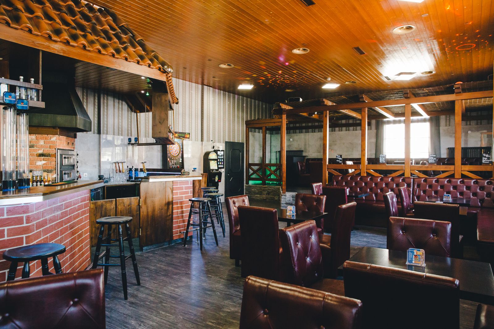 Die Bar mit Chesterfield-Ledersesseln unter einer warmen Holzdecke