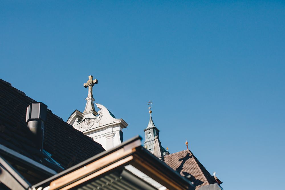 Kreuz und Turmspitze der Pfarrkirche vor klarem Sommerhimmel