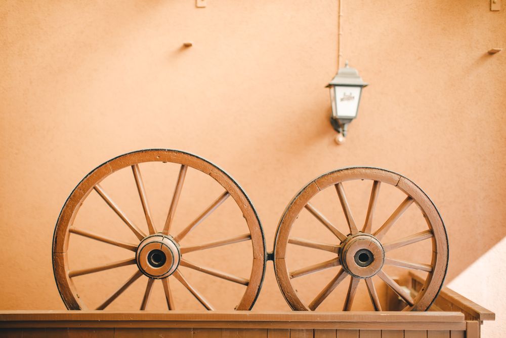 Traditionelle hölzerne Wagenräder als Dekoration an einer warmen ockerfarbenen Wand