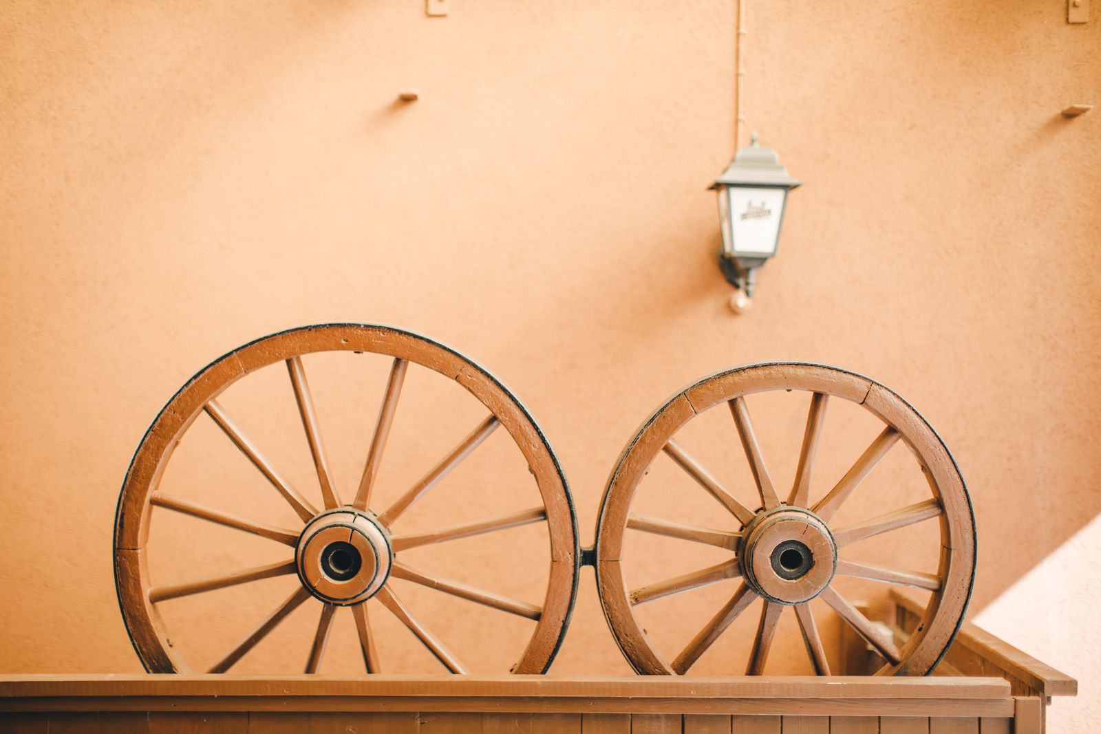 Traditionelle hölzerne Wagenräder als Dekoration an einer warmen ockerfarbenen Wand