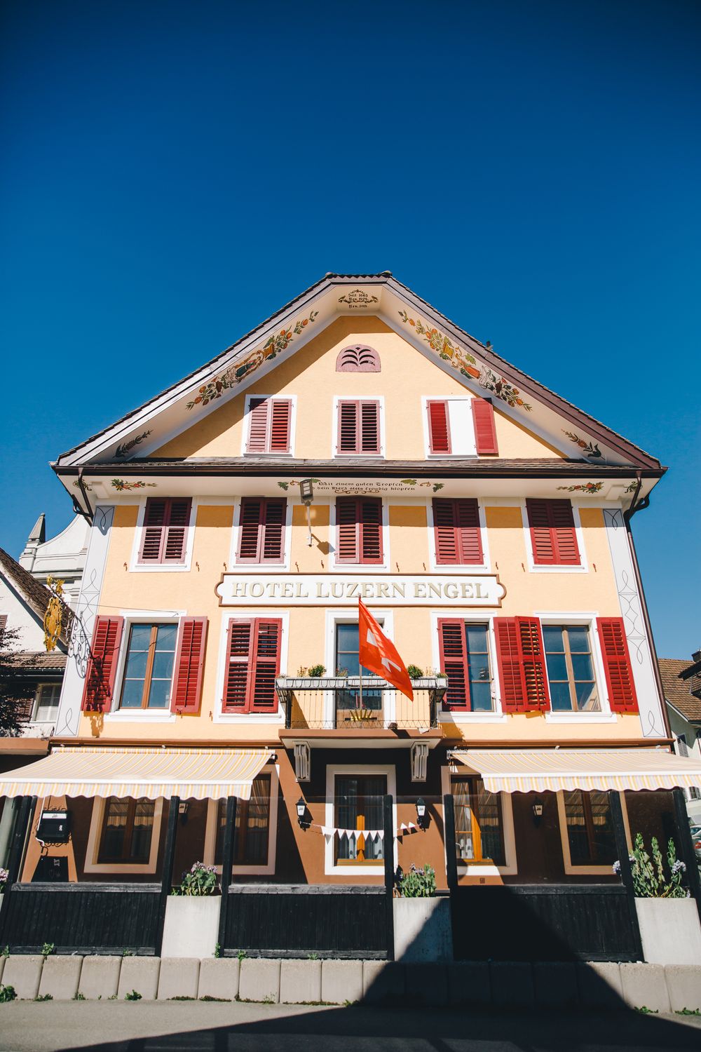 Die symmetrische Vorderfront des Hauses, das Hotelschild mittig unter dem bemalten Giebel