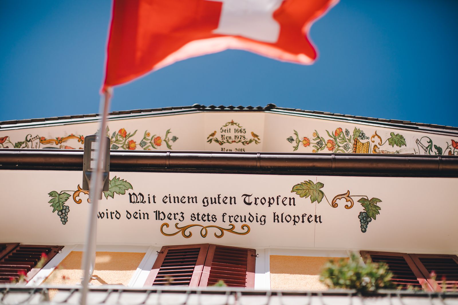 Die bemalte Kartusche am Giebel, die das Haus seit 1665 ausweist, darüber die Schweizer Fahne