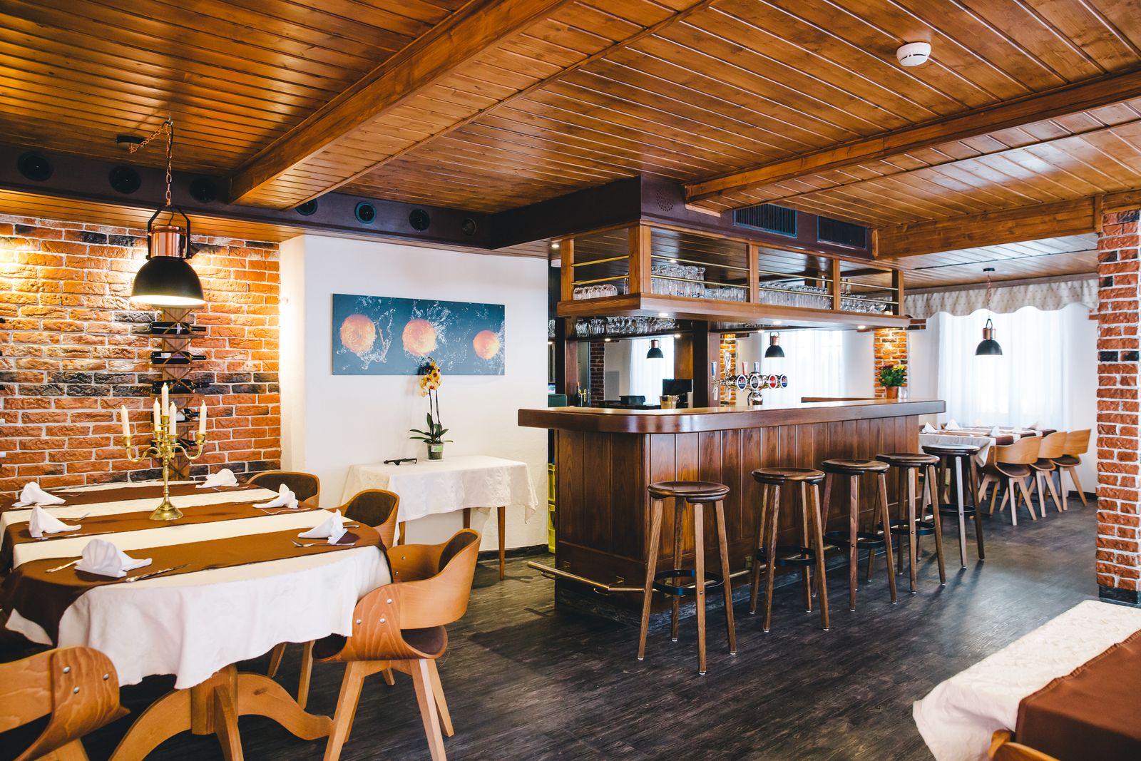 Das Restaurant unter der Holzdecke für den Service eingedeckt, dahinter der Tresen