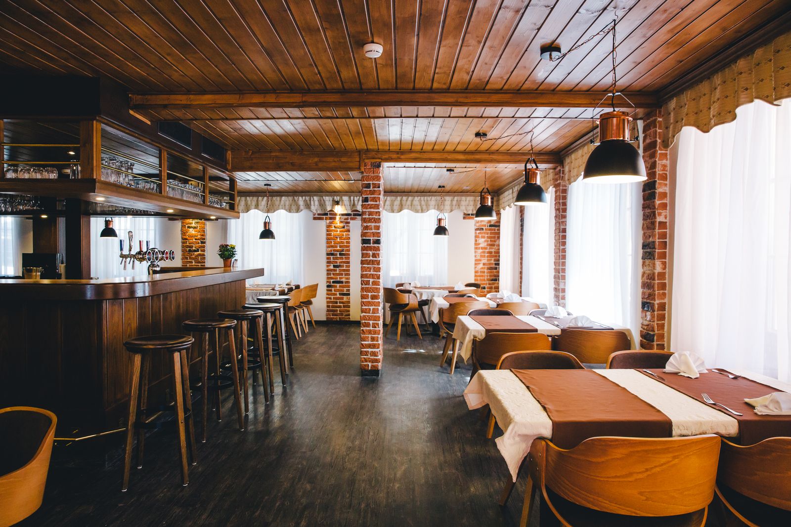 Der Speisesaal entlang der Bar, Ziegelsäulen tragen die Holzdecke