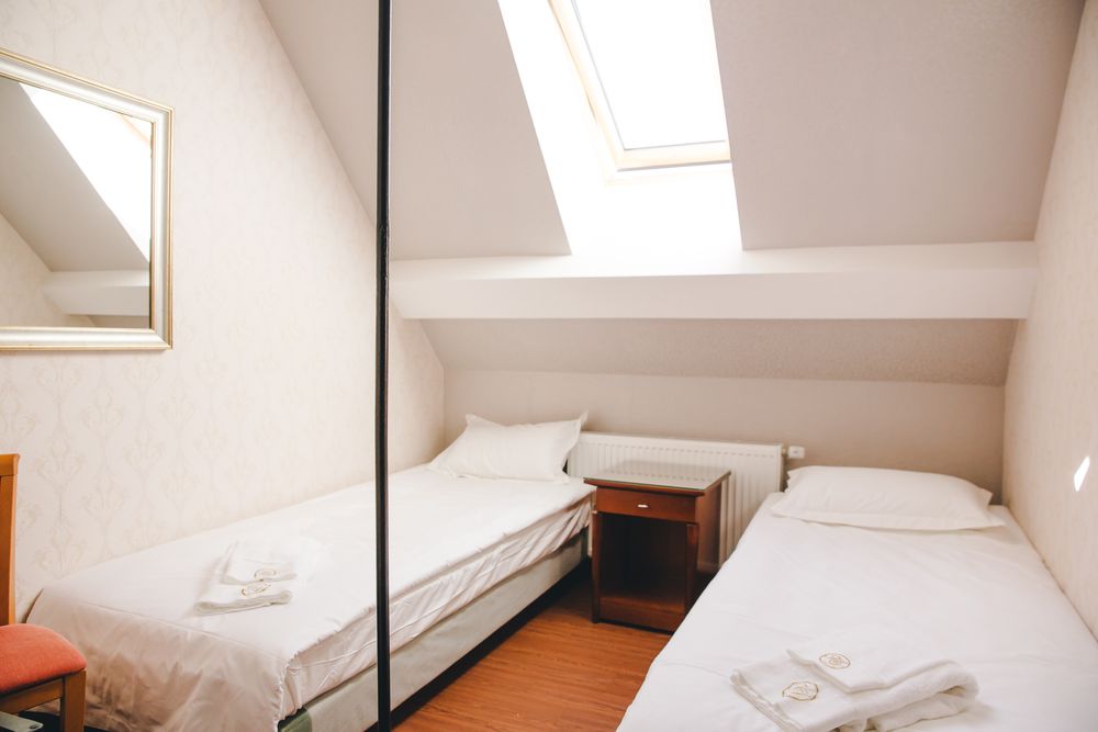 Zwei Einzelbetten unter einem Dachfenster in einem ruhigen Mansardenzimmer