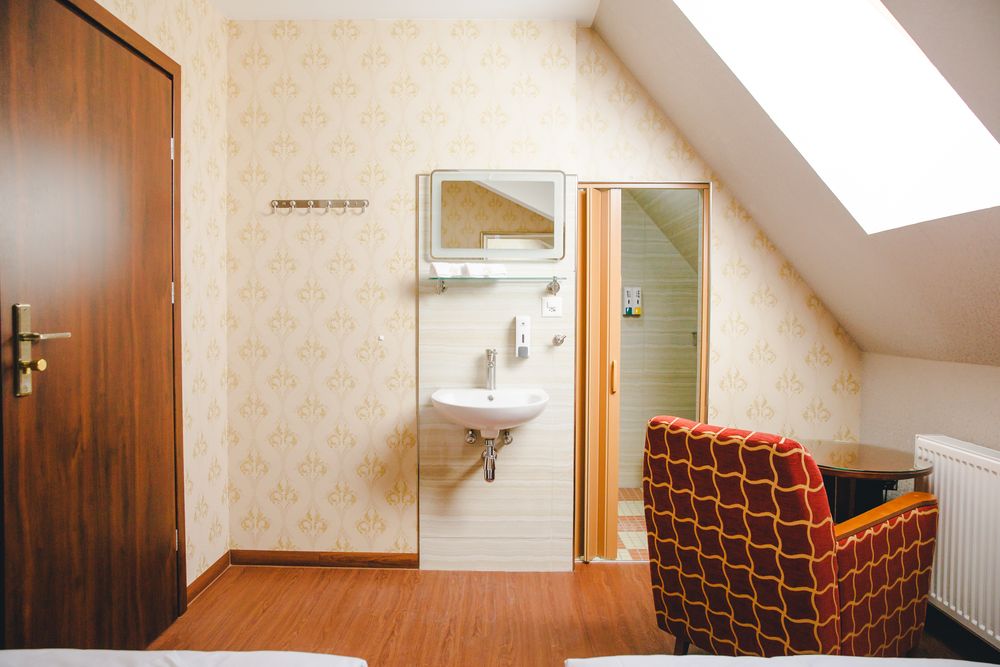 Ein Zimmer unter der Dachschräge mit Sessel und eigenem Duschbad