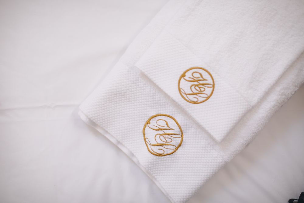 Auf dem Bett gefaltete Tücher, bestickt mit dem Monogramm des Hauses