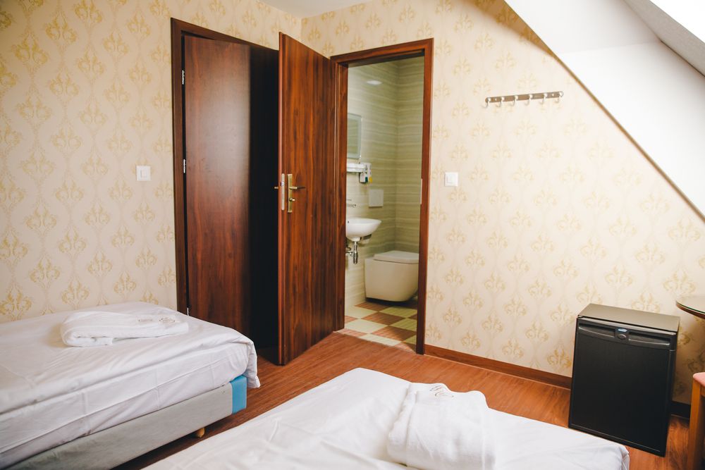 Ein Zweibettzimmer mit zwei Betten und geöffneter Tür zum eigenen Badezimmer