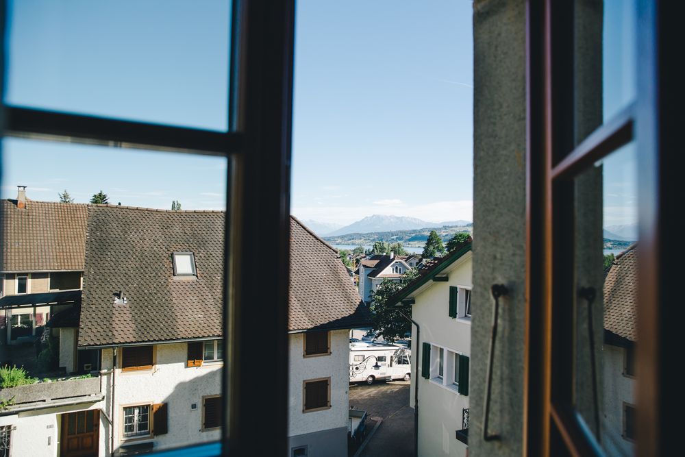 Der Blick aus einem Zimmerfenster über das Dorf zu den fernen Gipfeln